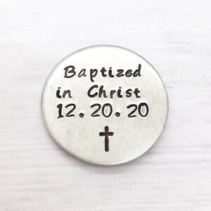 May include: Silver round charm with the text "Baptized in Christ 12.20.20" and a small cross.