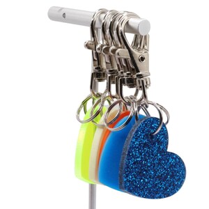 May include: A silver key chain holder with a blue glitter heart charm and three other colorful heart charms.