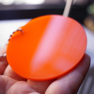May include: A bright orange round keychain with a silver chain.
