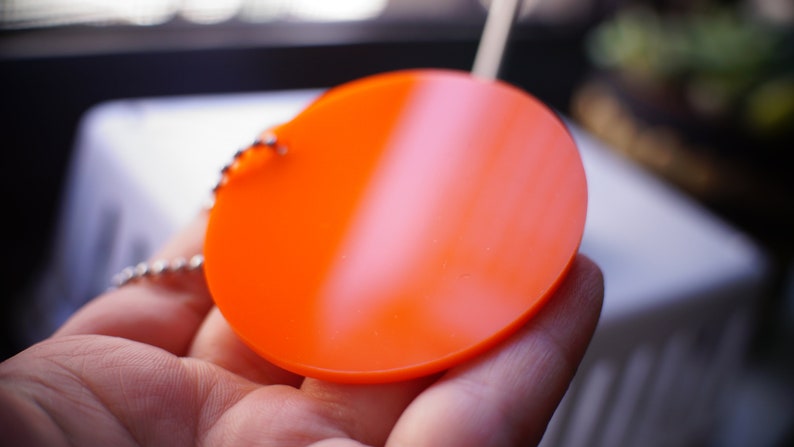 May include: A bright orange round keychain with a silver chain.
