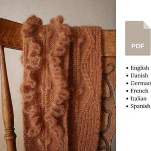 May include: A terracotta-coloured knitted scarf with a frilled edge is draped over a wooden chair. The scarf has a textured appearance with a detailed knit pattern. The image includes a PDF icon and a list of languages.