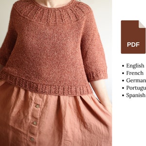 Peut inclure: Un pull en tricot de couleur rouille avec des manches courtes et un col côtelé. Le pull est porté sur une longue jupe boutonnée de couleur rouille.