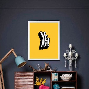 May include: A mid-century modern style wooden cabinet with a white door and open shelves. The cabinet is decorated with a variety of items, including a framed print with the word "Yeah!" in black and white on a yellow background, a ceramic skull, a ceramic hand, a bouquet of yellow flowers, and a bowl of white stones. The cabinet is sitting on a yellow and white patterned rug in front of a dark gray wall.