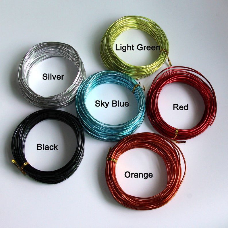 Op de afbeelding: Zes spoelen draad in verschillende kleuren: zilver, zwart, hemelsblauw, lichtgroen, rood en oranje.