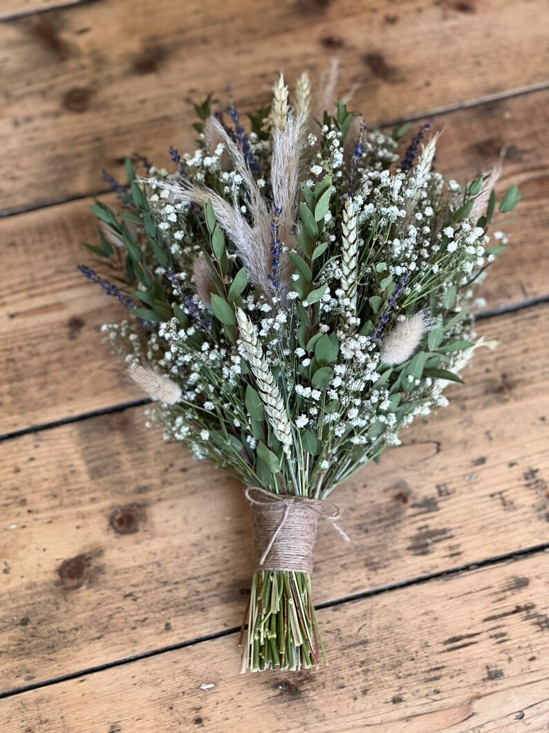 Puede incluir: Un ramo de novia r&uacute;stico con flores secas, incluyendo aliento de beb&eacute; blanco, trigo y lavanda.