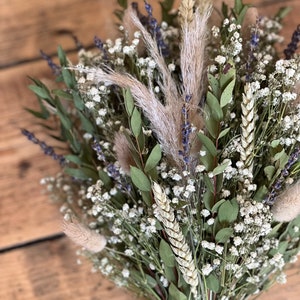 Puede incluir: Un ramo de flores secas con aliento de beb&eacute; blanco, tallos de trigo, lavanda y hierba de la pampa atados con cuerda.