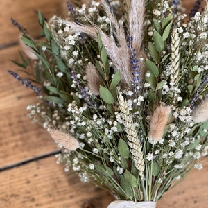 Puede incluir: Un ramo de flores secas con aliento de beb&eacute; blanco, lavanda seca, trigo y hierba de la pampa marr&oacute;n claro y esponjosa, atado con una cinta de sat&eacute;n blanca.