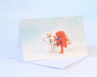 A choice of One or Four blank greeting cards of Rabbit bunny making a snowman