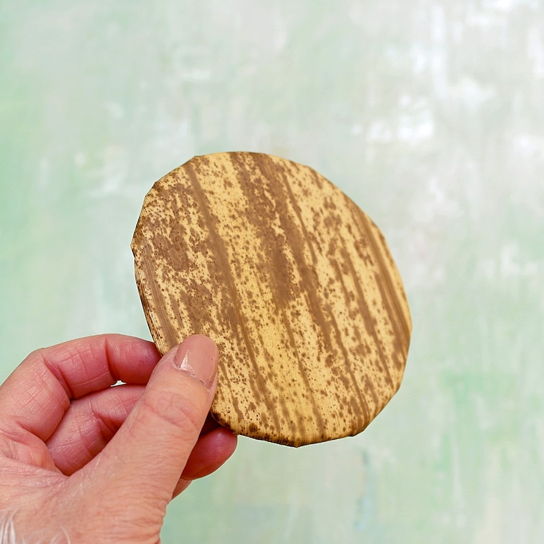 May include: A round, brown and tan coaster with a striped pattern. The coaster is made from natural materials and has a rustic look.