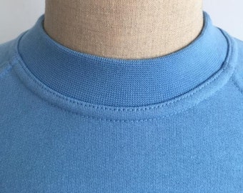 May include: A light blue crew neck t-shirt on a mannequin.