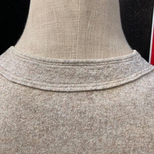 Puede incluir: Primer plano del cuello de un su&eacute;ter marr&oacute;n. El su&eacute;ter tiene un cuello de canal&eacute; y una tela suave y texturizada.