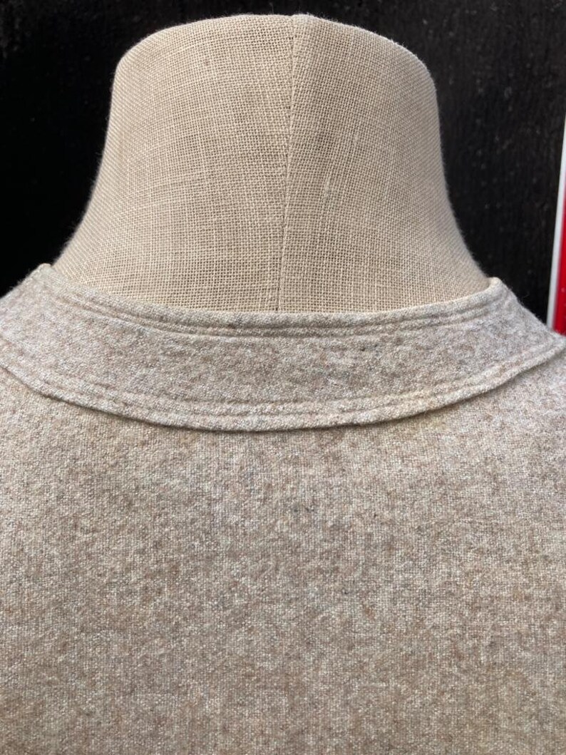 Puede incluir: Primer plano del cuello de un su&eacute;ter marr&oacute;n. El su&eacute;ter tiene un cuello de canal&eacute; y una tela suave y texturizada.