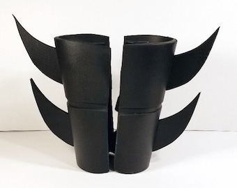 May include: A pair of black foam costume gauntlets with pointed, jagged edges. The gauntlets are designed to resemble claws or fangs.