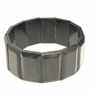 May include: A black bracelet made of rectangular obsidian beads. The bracelet is flexible and has a simple design.