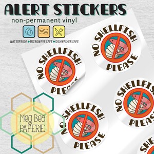 May include: Five round, white, non-permanent vinyl stickers with a red circle and a diagonal line through a shrimp and a seashell. The text "NO SHELLFISH PLEASE" is written in brown around the red circle.