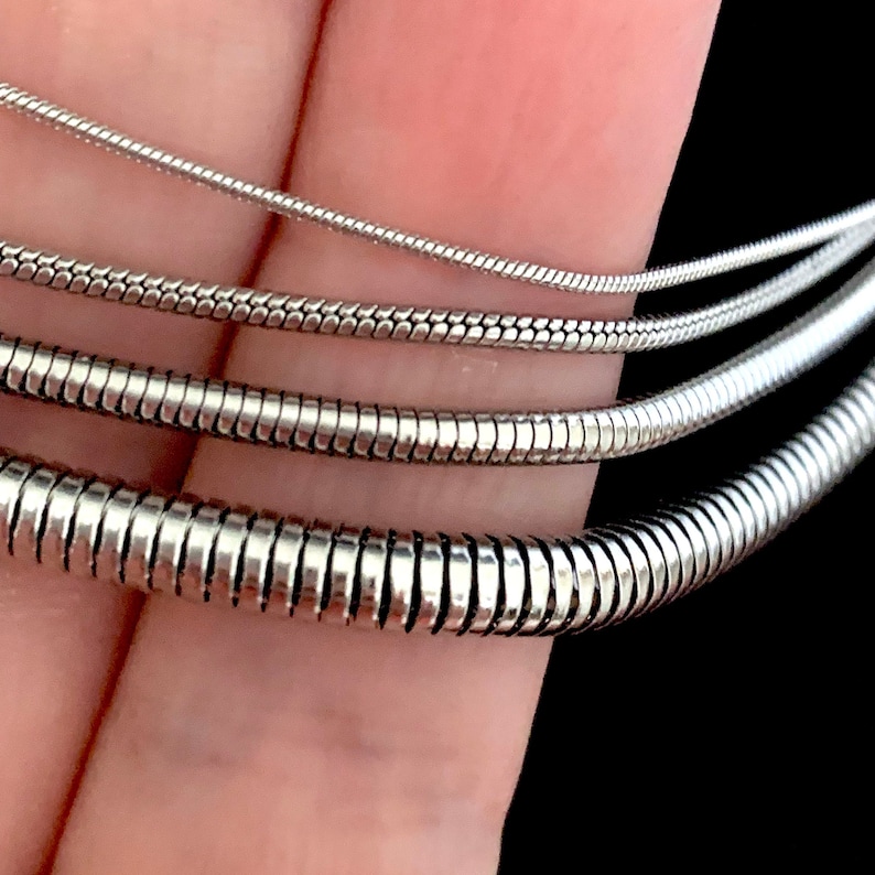 Close up of Silver Color Snake Chain Necklace. Snake Chain Necklace design in silver color made of 316L Stainless Steel.  Great wearing with no tarnishing. Nice for gift giving for Men or Women. Widths include 1mm, 1.5mm, 2.4mm and 4mm.