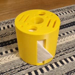 May include: A yellow 3D printed tissue holder with a slot for a tissue box and multiple holes for storing other items.