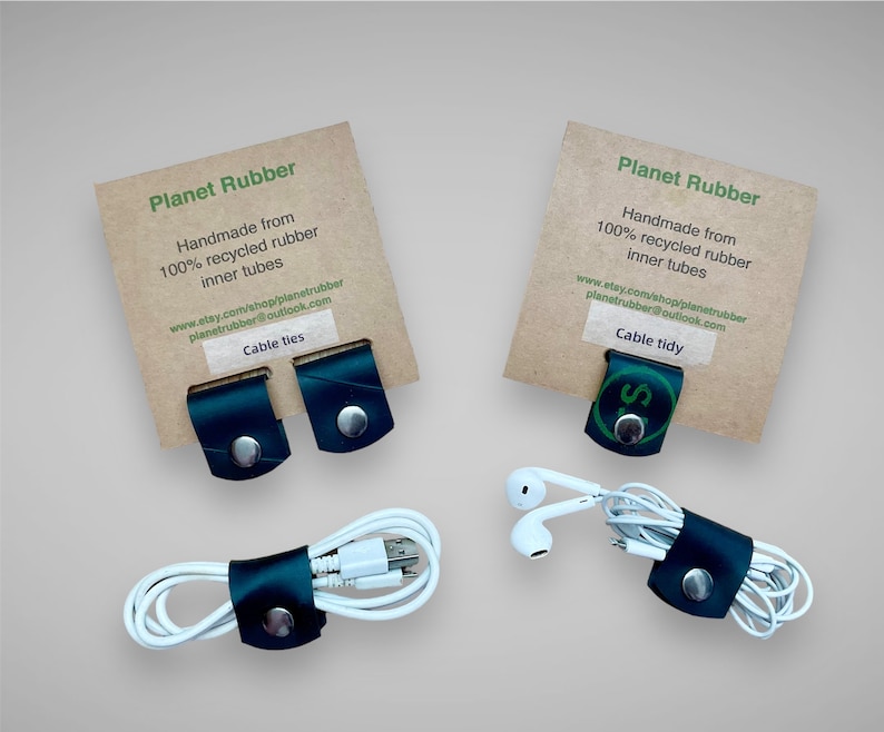 May include: Two sets of black leather cable ties made from recycled inner tubes. The cable ties are shown holding a white charging cable and a pair of white earbuds. The packaging is brown cardboard with the text "Planet Rubber" and "Handmade from 100% recycled rubber inner tubes" printed in green.