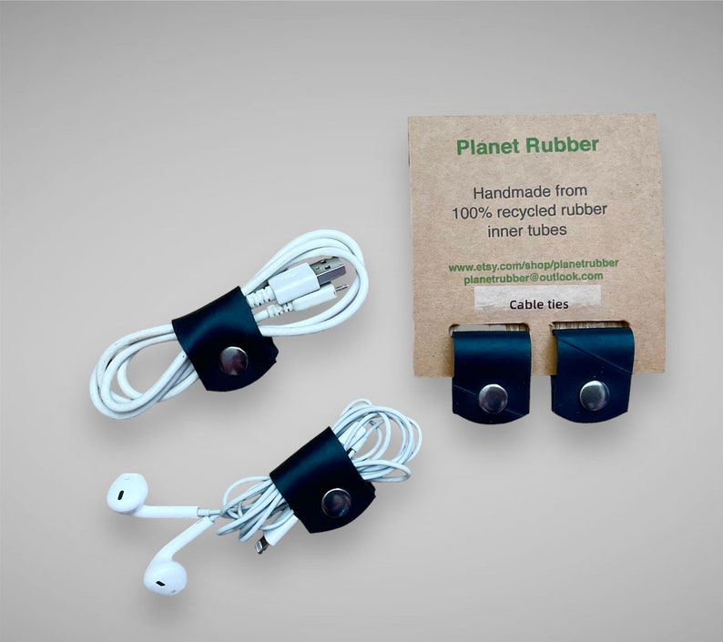 May include: Three black leather cable ties made from 100% recycled inner tubes. The cable ties are shown holding together various cords and wires. The text on the card reads "Planet Rubber Handmade from 100% recycled rubber inner tubes www.etsy.com/shop/planetrubber planetrubber@outlook.com Cable ties"