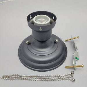 May include: A gray metal ceiling light fixture with a white porcelain socket, a chain, and a mounting bracket. The fixture has a round base and a decorative design.