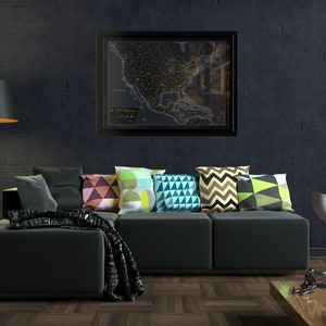 May include: A black sectional sofa with a variety of colourful throw pillows. The sofa is in front of a dark brick wall with a framed map of the United States hanging above it.