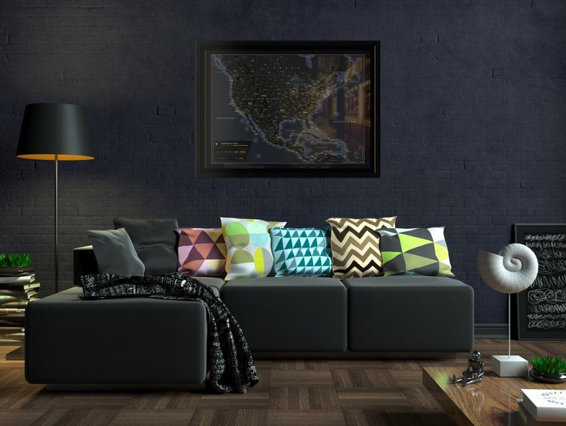May include: A black sectional sofa with a variety of colourful throw pillows. The sofa is in front of a dark brick wall with a framed map of the United States hanging above it.
