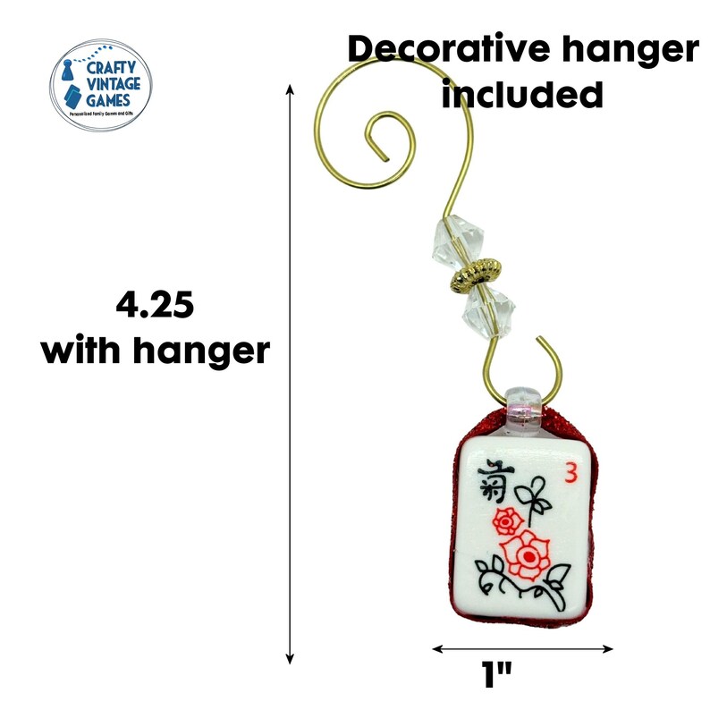 Puede incluir: Adorno decorativo de ficha de Mahjong con un colgador dorado. La ficha es blanca con dise&ntilde;os florales rojos y el n&uacute;mero 3. El adorno mide 10,8 cm con el colgador y 2,5 cm de ancho.