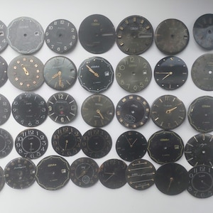 Pode incluir: Uma coleção de mostradores de relógios vintage em vários tons de preto e cinza. Os mostradores exibem números e ponteiros, alguns com detalhes dourados. A variedade inclui diferentes estilos e designs, mostrando uma gama de relógios.