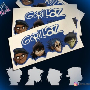 May include: Four white silhouette stickers of the Gorillaz band members, 2D, Noodle, Russel, and Murdoc, on a blue background with the band's name in white. The stickers are on top of three white stickers with the band's name in white on a blue background. The band members' faces are visible on the stickers.