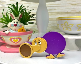 May include: A purple and brown toy bird with a cartoon face. The bird is made of plastic and has a round body and a long beak.