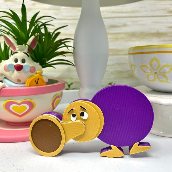 May include: A purple and brown toy bird with a cartoon face. The bird is made of plastic and has a round body and a long beak.