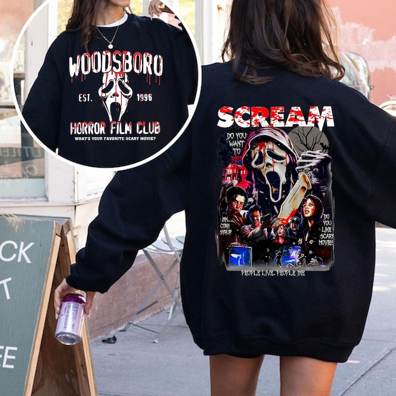 May include: Black sweatshirt with "WOODSBORO" and a ghost face graphic. The front of the sweatshirt has "HORROR FILM CLUB" text. The back features "SCREAM" text and a movie poster graphic with the text "DO YOU WANT TO" and "PEOPLE LIVE, PEOPLE DIE".