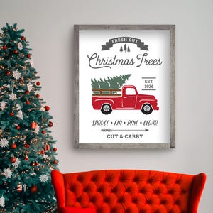 Pu&ograve; includere: Un cartello bianco con un camioncino rosso che trasporta un albero di Natale. Il cartello dice "Fresh Cut Christmas Trees Est. 1936 Spruce Fir Pine Cedar Cut & Carry"