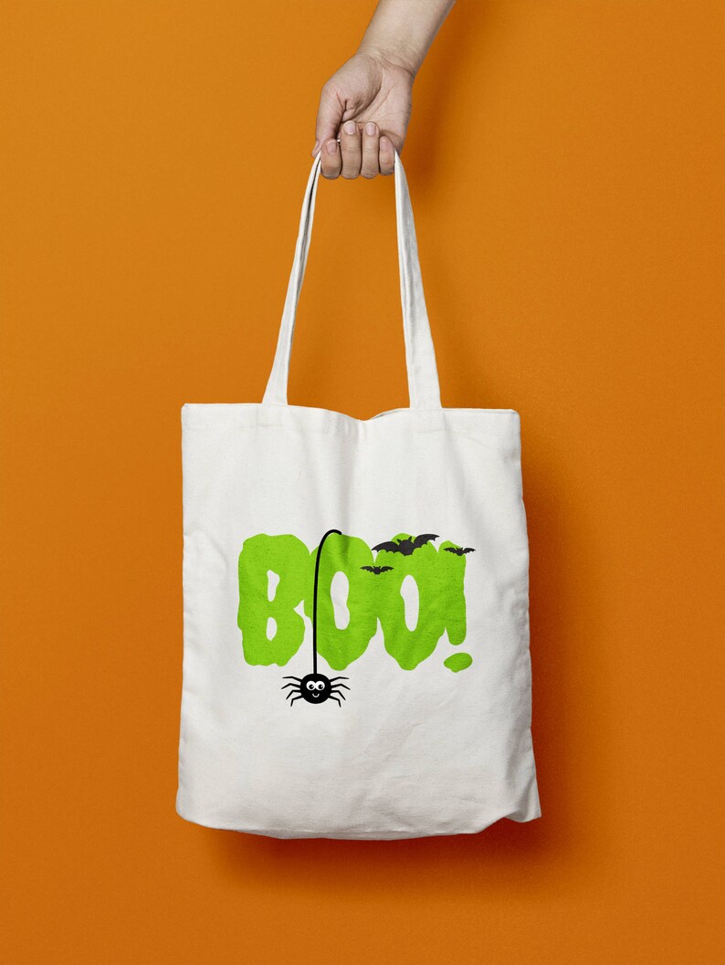 May include: White canvas tote bag with a green "BOO!" graphic and a black spider hanging from the "O". There are also black bats flying above the text.
