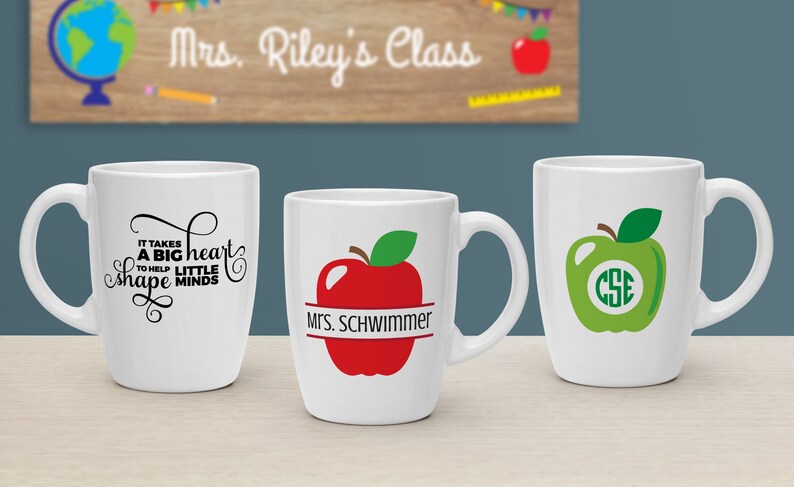 Puede incluir: Tres tazas de cer&aacute;mica blanca con diferentes dise&ntilde;os. La primera taza tiene texto negro que dice "Se necesita un gran coraz&oacute;n para ayudar a los peque&ntilde;os a moldear las mentes". La segunda taza tiene una manzana roja con una hoja verde y una pancarta negra que dice "Mrs. Schwimmer". La tercera taza tiene una manzana verde con una hoja verde y un c&iacute;rculo blanco con las letras "CSE" dentro.