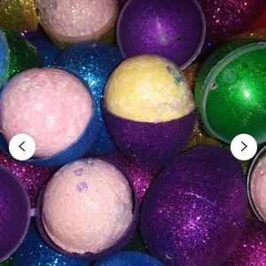 May include: A close-up of a variety of bath bombs, each encased in a glittery sphere. The bath bombs are in shades of pink, yellow, blue, green, and purple.