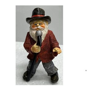 May include: A figurine of a singing Santa Claus. The figure wears a black hat, a red jacket, gray pants, and black shoes. He holds a microphone and has a long white beard. The figurine is a decorative item.