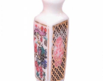 May include: A small white porcelain vase with a square base and a narrow neck. The vase is decorated with a colorful floral pattern and a gold geometric design.