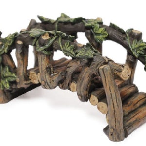 Könnte beinhalten: Eine Miniatur-Holzbrücke mit einem von Ranken bewachsenen Torbogen. Die Brücke besteht aus braunen Baumstämmen und hat eine grüne, belaubte Rankenpflanze, die über die Oberseite wächst. Die Brücke ist perfekt für einen Feengarten oder eine andere Miniatur-Szene.