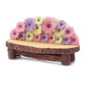 May include: A miniature wooden bench with a floral design. The bench is decorated with pink, purple, and yellow flowers.