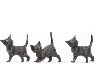 Könnte beinhalten: Drei kleine, dunkelgraue Katzenfiguren werden vor einem weißen Hintergrund gezeigt. Jede Katze befindet sich in einer anderen Pose, eine geht, eine streckt sich und eine schaut zur Seite. Die Figuren haben ein strukturiertes Aussehen.