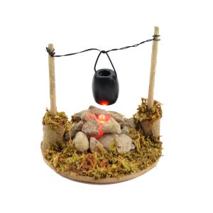 May include: A miniature campfire scene with a black pot hanging over the flames. The campfire is made of small rocks and has a glowing red light. The scene is set on a wooden base with green moss.