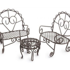 Op de afbeelding: Een set van drie miniatuur metalen tuinmeubelen, waaronder twee stoelen en een tafel. De stoelen hebben een hartvormig ontwerp en de tafel is rond. De meubels zijn in een donkerbruine kleur geverfd.
