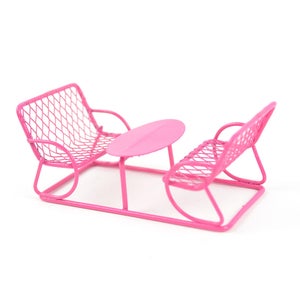 May include: Pink metal patio furniture set with two chairs and a table. The chairs and table are made of wire mesh and have a pink finish.