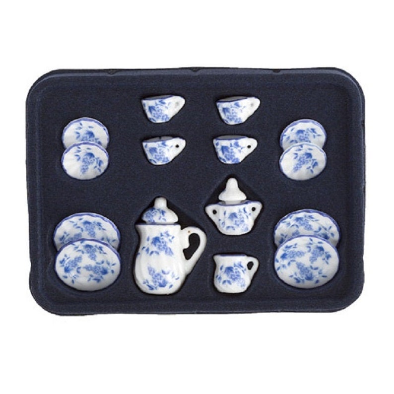 May include: A blue and white porcelain tea set in a black tray. The set includes a teapot, creamer, sugar bowl, four cups, and four saucers.