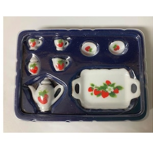May include: A white porcelain tea set with a strawberry design. The set includes a teapot, creamer, sugar bowl, four cups, and a serving tray. The set is packaged in a blue and white box.