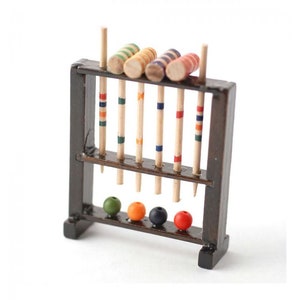 May include: A miniature wooden croquet set with six mallets and five balls. The mallets are striped with red, blue, and yellow. The balls are green, orange, and red.