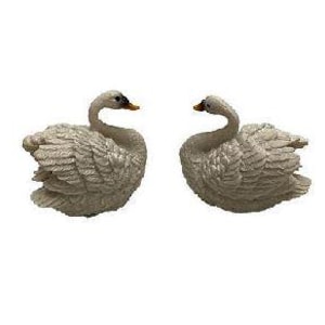 May include: Two white swan figurines facing each other. The swans have detailed feathers and are in a curled position.