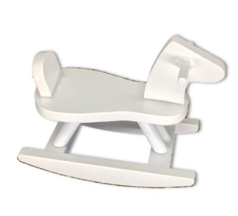 Puede incluir: Juguete de caballo de balanc&iacute;n de madera blanco para ni&ntilde;os. El caballo tiene un dise&ntilde;o sencillo con una cabeza redondeada y una silla de montar.