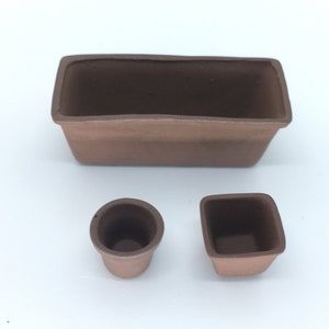 May include: Three terracotta pots, one rectangular and two round, for planting small plants or succulents.